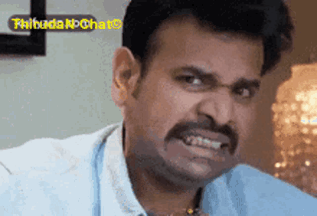 a man with a mustache is making a funny face in front of a sign that says thiruda k chat