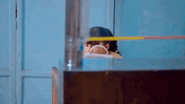 a woman is peeking out from behind a glass door while holding a tablet .