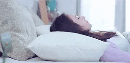 a woman is laying on a bed with a pillow on her head .