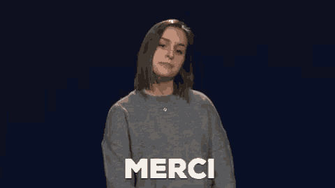 a woman in a grey sweater says merci in french