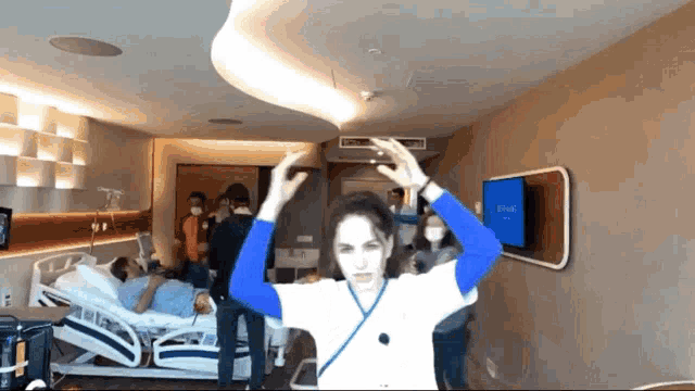 a woman stands in front of a hospital bed with a tv on the wall that says ambulance