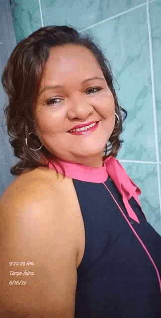 a woman wearing a black top with a pink collar smiles for the camera