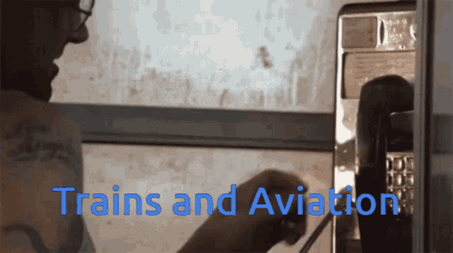 a man is talking on a pay phone and the words trains and aviation are on the screen