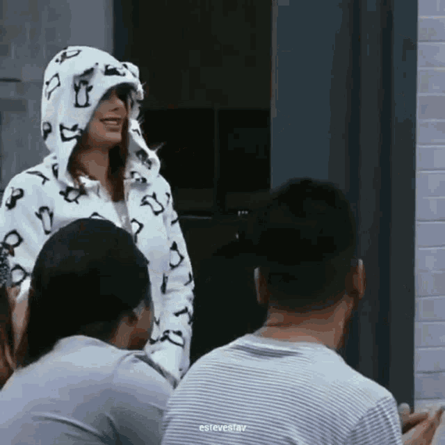a woman wearing a penguin hooded jacket is standing in front of a group of people