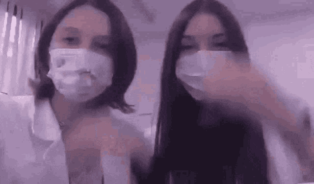 two young women wearing face masks are standing next to each other .