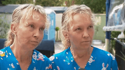 two women are wearing blue scrubs with rabbits on them and looking at each other .
