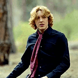 a man with blonde hair wearing a black shirt and a red scarf