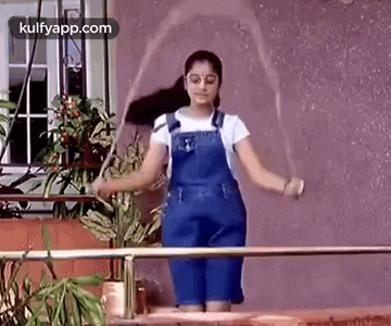 a girl is jumping a jump rope on a balcony .