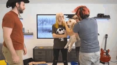 a man wearing a cowboy hat is petting a dog in a living room .