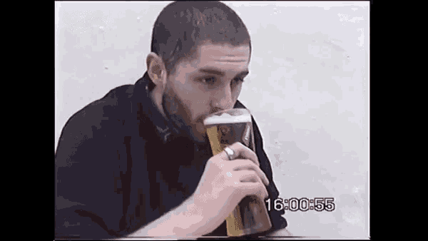 a man is drinking a glass of beer with the time of 16 00 55