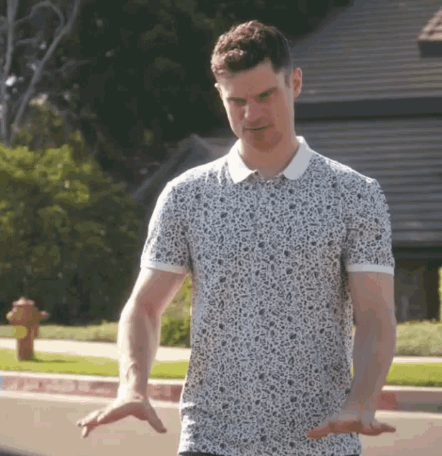 a man wearing a white shirt with a leopard print on it is standing in front of a fire hydrant