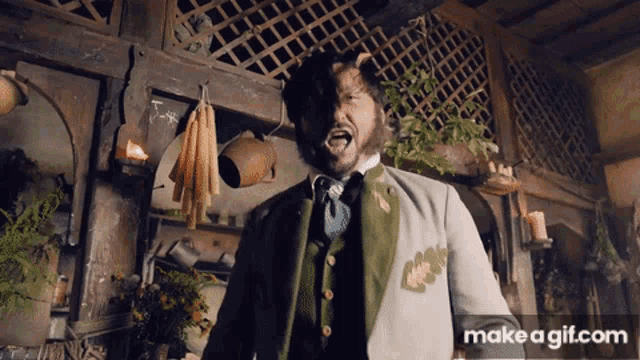 a man in a green vest is screaming in front of a make a gif website