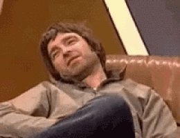 a man is sitting in a chair with his legs crossed and his head down .