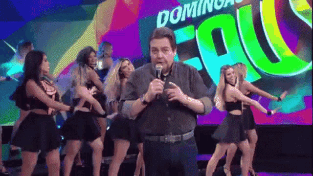 a man is holding a microphone in front of a sign that says domingos