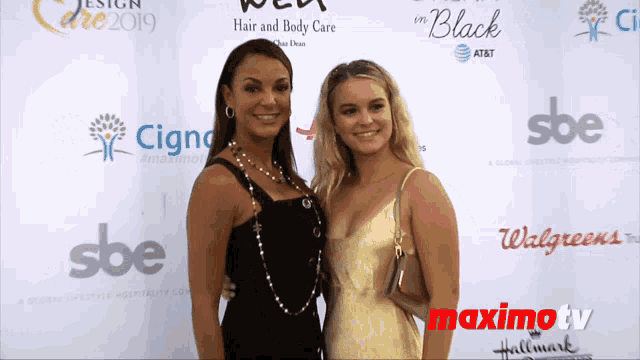two women are posing for a picture in front of a wall that says maximtv