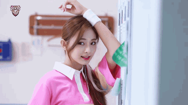 a girl in a pink shirt is standing in front of a locker with a twice logo on it