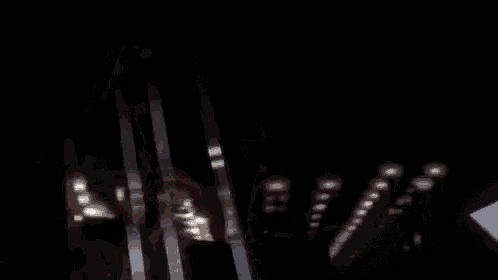a person is walking through a dark room with a lot of lights behind them .