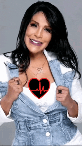 a woman in a denim jacket has a heart with a heartbeat on it and the letter sa on her necklace