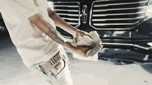 a man is holding a stack of money in front of a lincoln continental .