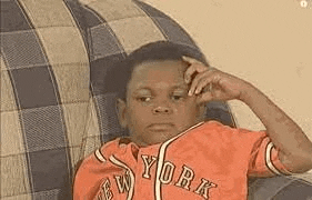 a young boy in a new york jersey is sitting on a couch with his hand on his head .