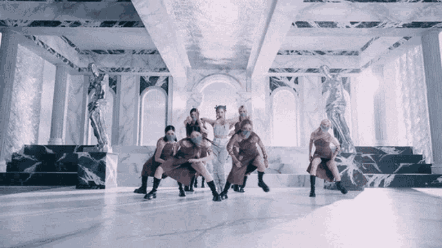 a group of people wearing masks are dancing in a room with marble walls