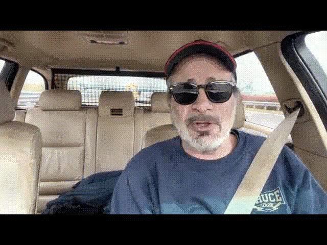 a man wearing sunglasses and a blue shirt that says bruce on it
