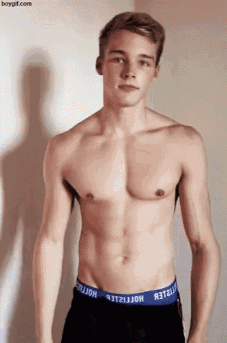 a shirtless young man wearing hollister underwear is standing in front of a white wall .