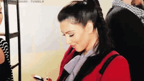 a woman in a red coat is looking at her cell phone .