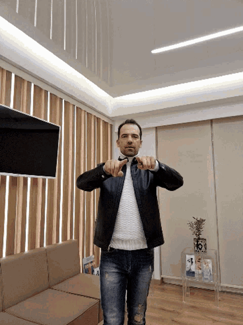 a man wearing a leather jacket and a bow tie is giving a thumbs down sign