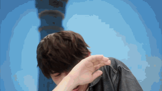 a person covering their face with their hand with a blue background