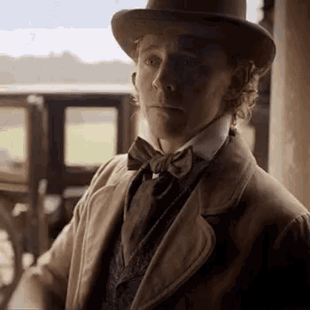 a man wearing a top hat and bow tie is standing in front of a car .