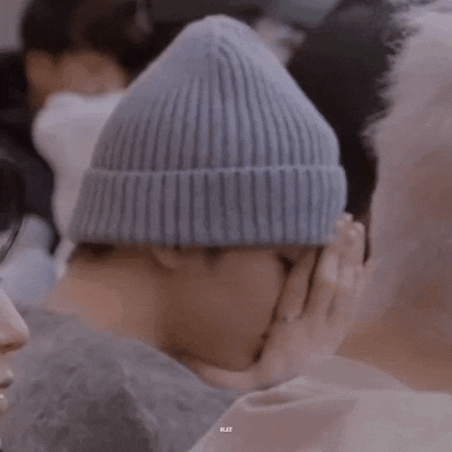 a person wearing a gray beanie is kissing another person 's face .