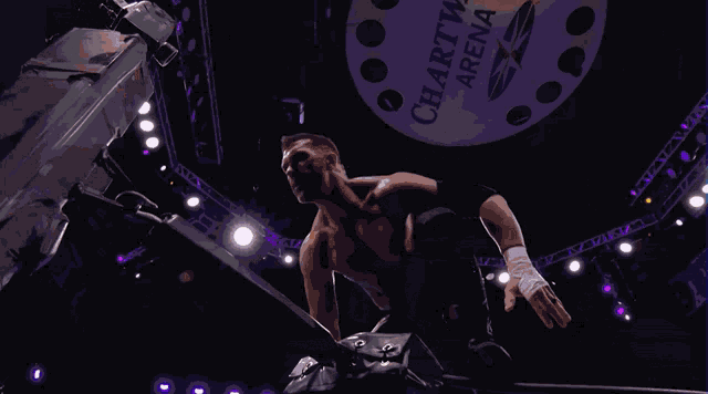 a wrestler is jumping in the air in front of a sign that says aew