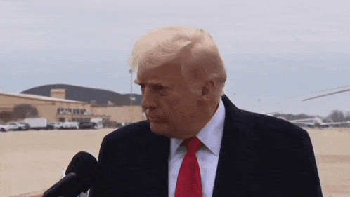 donald trump speaking into a microphone in front of a building that says ' donald ' on it