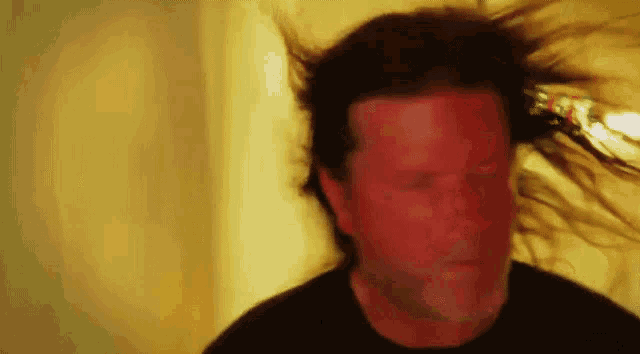 a man 's hair is blowing in the wind and his face is blurred .