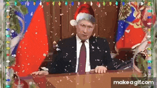 a man in a suit and tie is wearing a santa hat while sitting at a table .