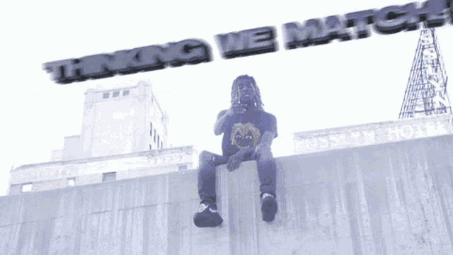 a man is sitting on a ledge with the words thinking we match behind him