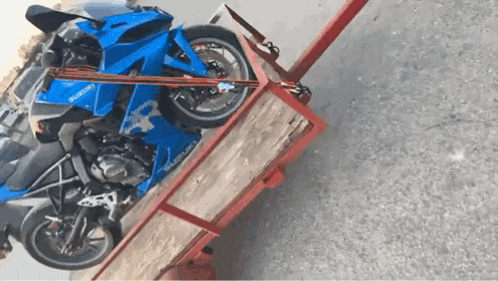 a blue suzuki motorcycle sits on a trailer
