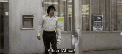 a man in a white shirt and black pants is walking down the street and says attica ! attica !