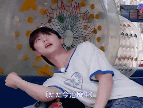 a man in a white shirt with a shark on it is sitting in front of a ferris wheel