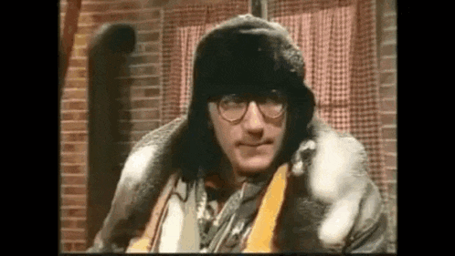 a man wearing a fur hat and glasses is sitting in a chair .
