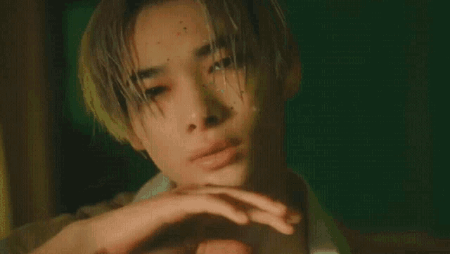 a close up of a young man covering his face with his hands