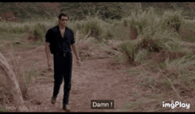 a man is walking in a field with a pile of dirt in the background .