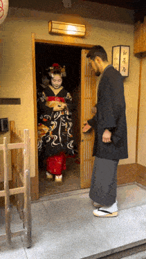 a man in a kimono stands in front of a doorway with a sign that says ' a ' on it