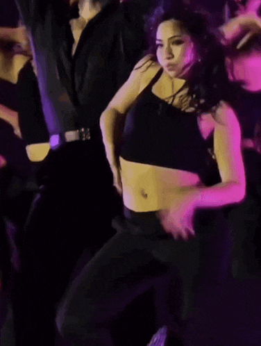 a woman in a crop top is dancing in a dark room