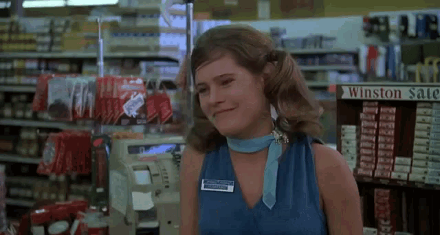 a woman in a blue shirt is smiling in front of a sign that says winston sale