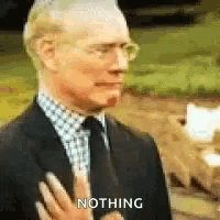 a man in a suit and tie is holding his hand to his chest and says nothing .