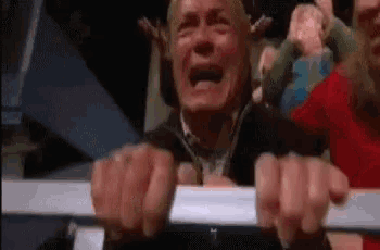 a man is crying while holding onto a railing in a crowd .