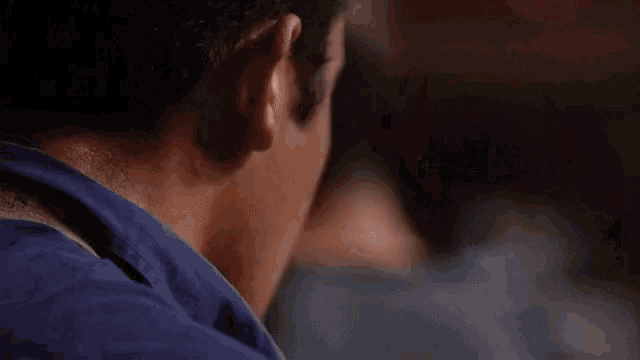 a man in a blue shirt is holding a red pepper in his hands .