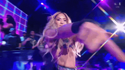 a woman is dancing on a stage in front of a crowd while holding a microphone in her hand .